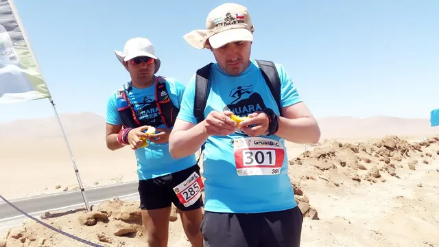 Dos participantes con poleras azules junto a una mesa de abastecimiento en Huara Desert 2018.