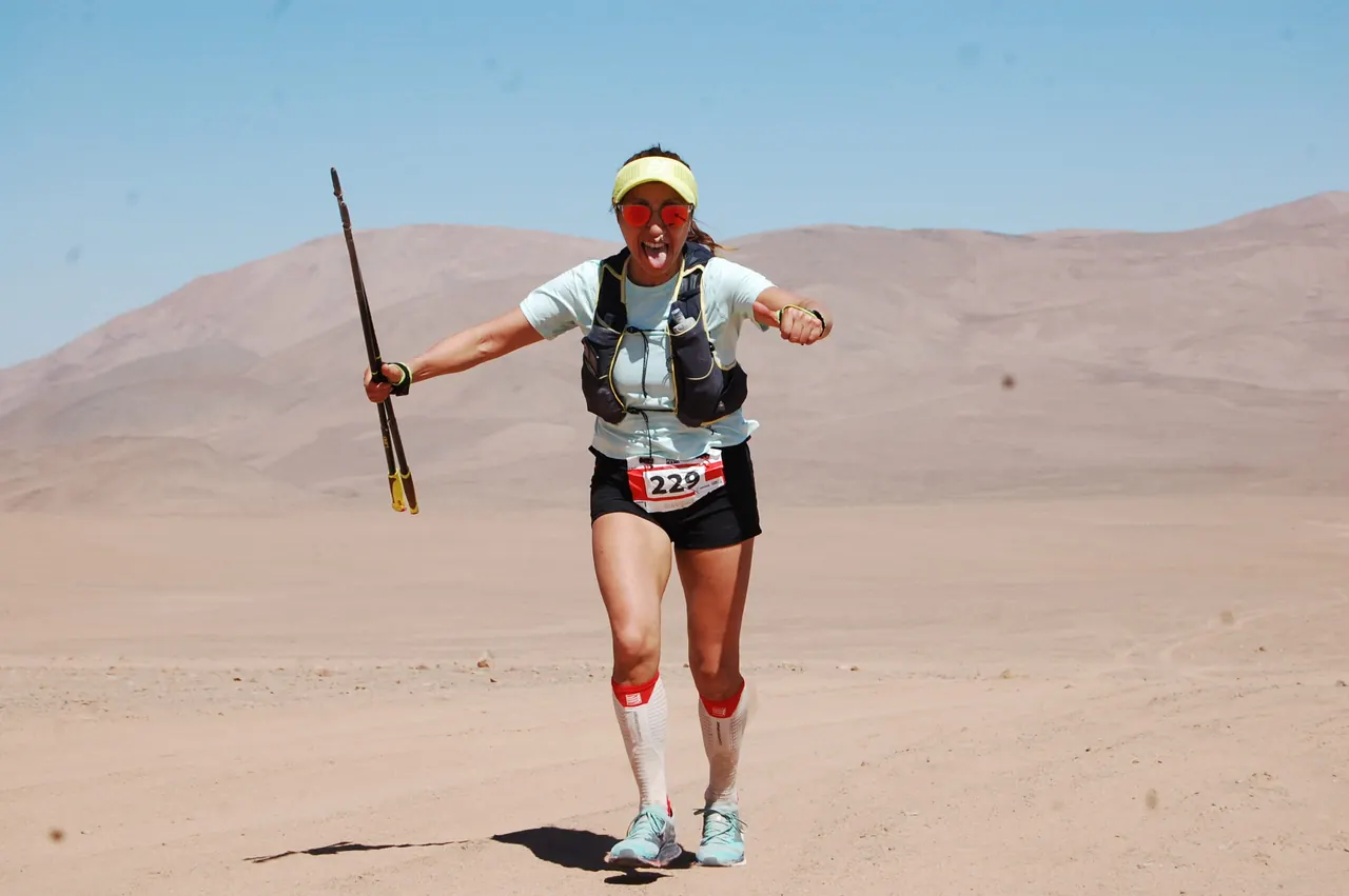 Corredora con bastones avanza por la arena en el desierto