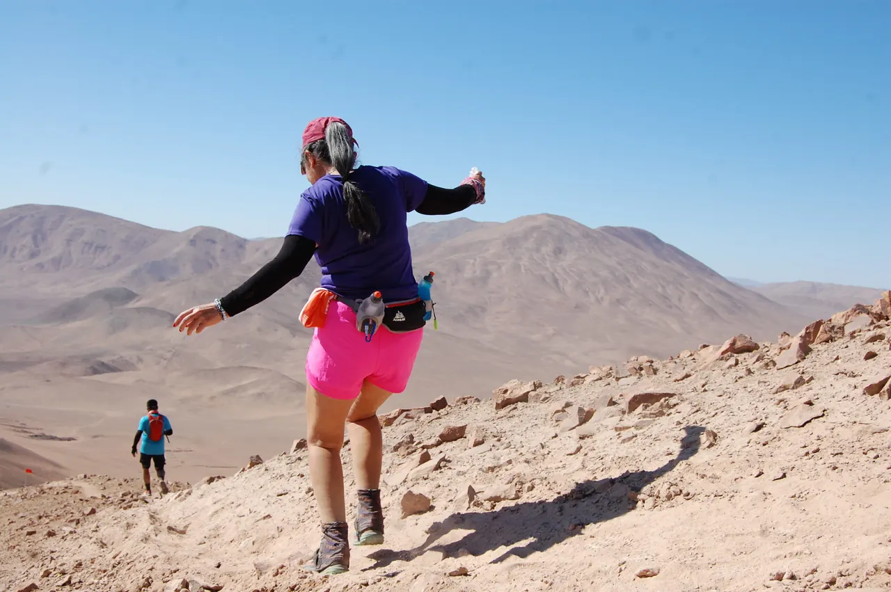 Deportista baja una ladera con cerros del desierto al fondo