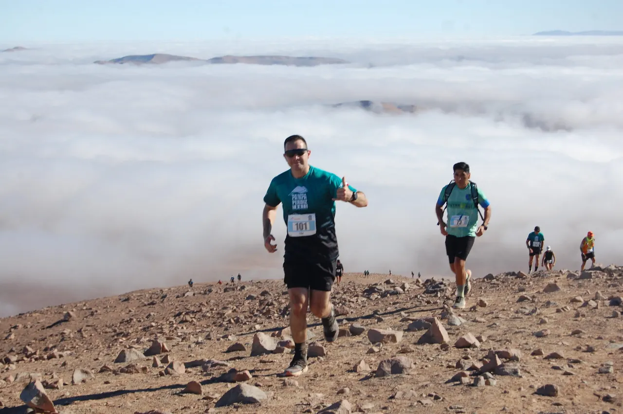 Corredores de Pampa Perdiz Trail suben una ladera sobre el mar de nubes